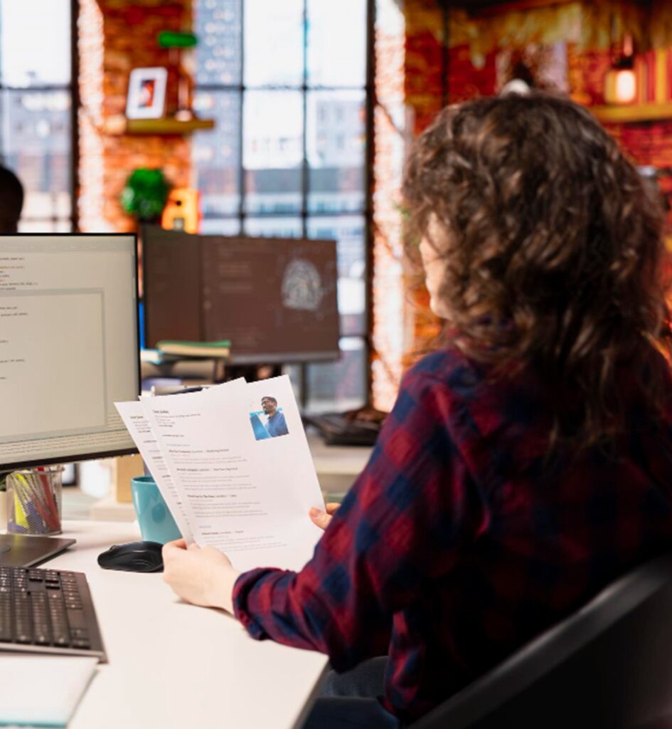 une femme regardant un cv devant son ordinateur